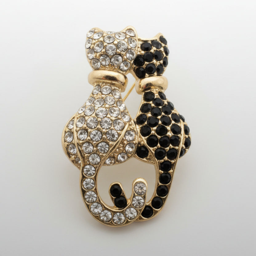Black and white rhinestone double  cat brooch on a light gray background