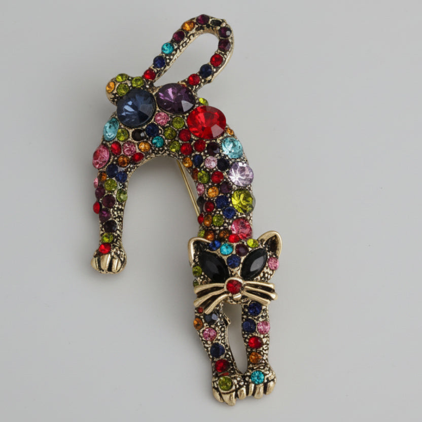 Colorful cat-shaped brooch with rhinestones on a light gray background