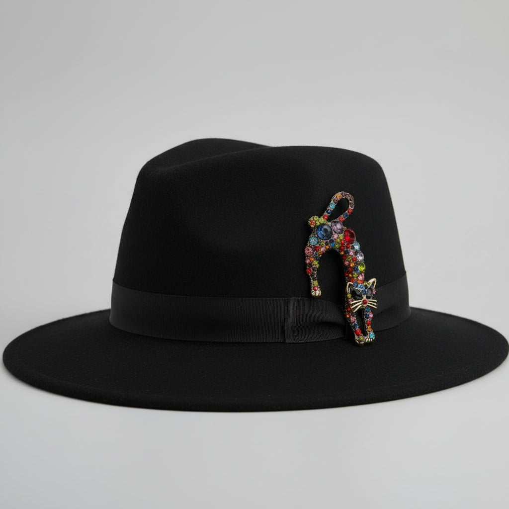 Colorful rhinestone cat-shaped brooch pinned on a black top hat, against a light gray background
